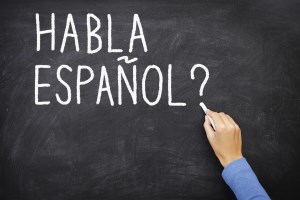 Spanish language learning concept image. Teacher or student writing "habla espanol" on blackboard during spanish language course class. S